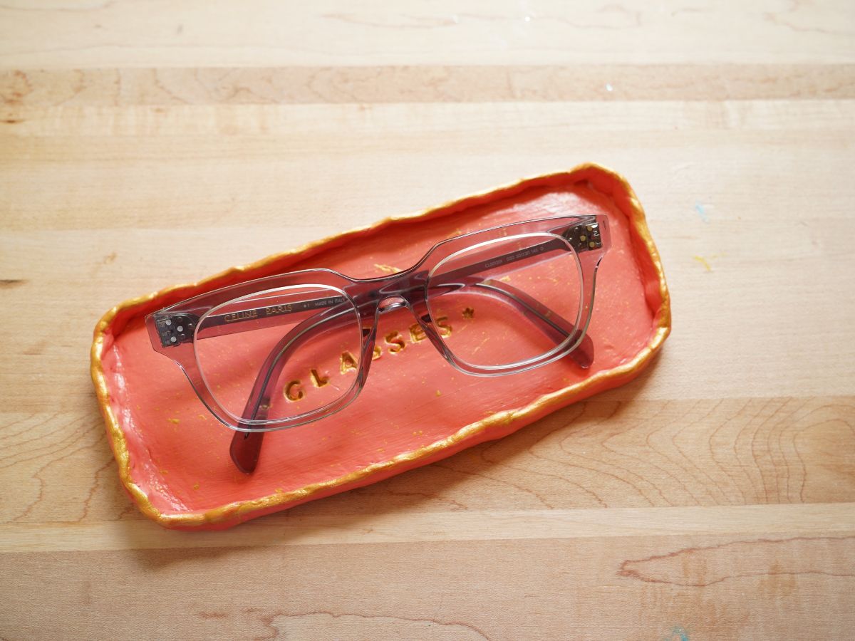 pair of eyeglasses in clay glasses tray on table