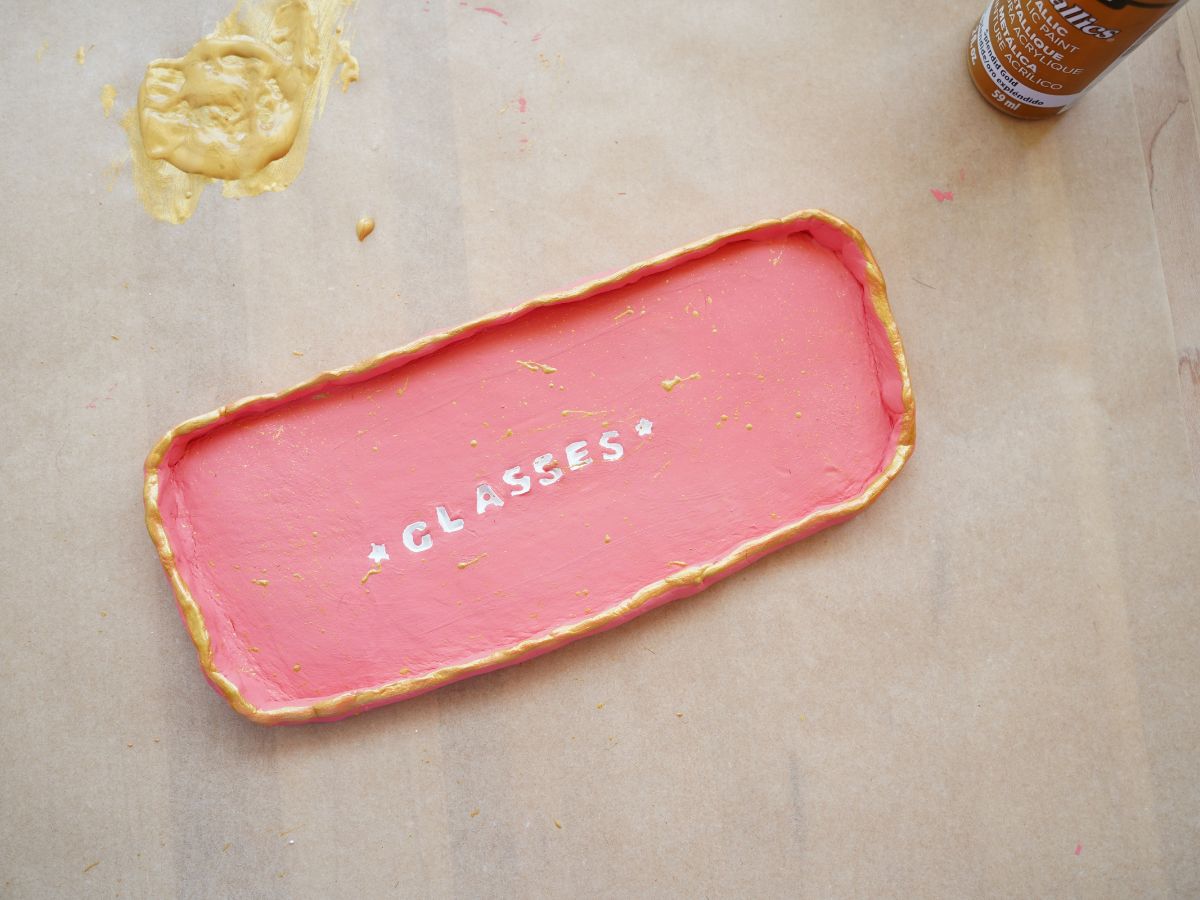 trinket tray painted with gold around edge and a puddle of gold paint