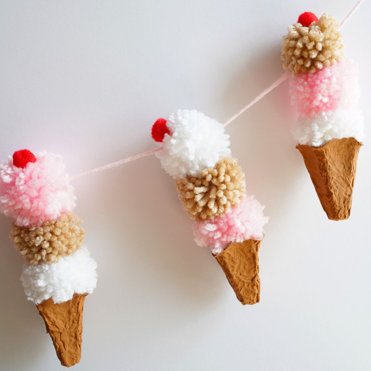 3 egg carton ice cream cones with pom pom ice cream and cherry on top garland