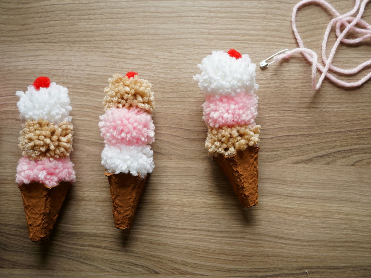 3 pompom ice cream cones on table with string with safety pin on table