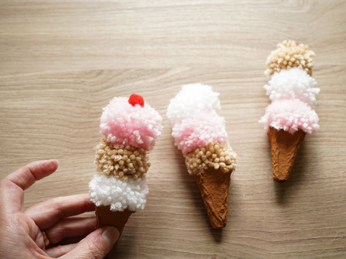 hand holding diy neopolitan color pompom ice cream cone with little red cherry pompom on top
