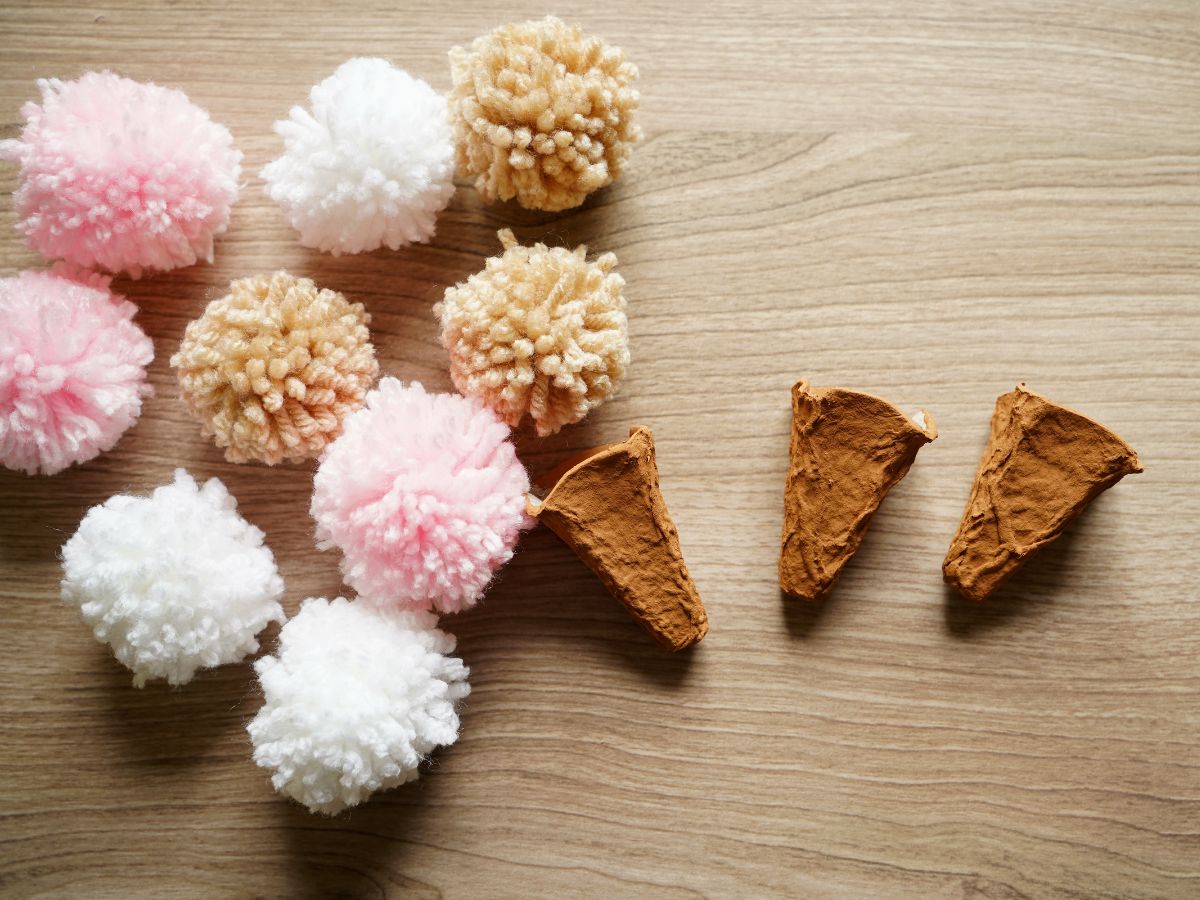 pile of ice cream colored pompoms and egg carton ice cream cones sitting on table