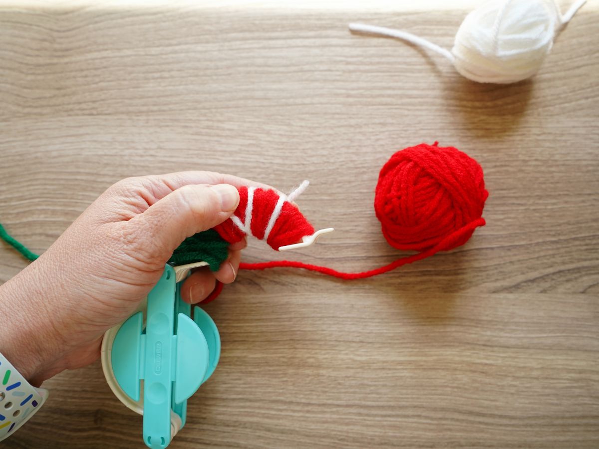 red and white yarn wrapped around pom pom maker tool for seeds of pom pom strawberry