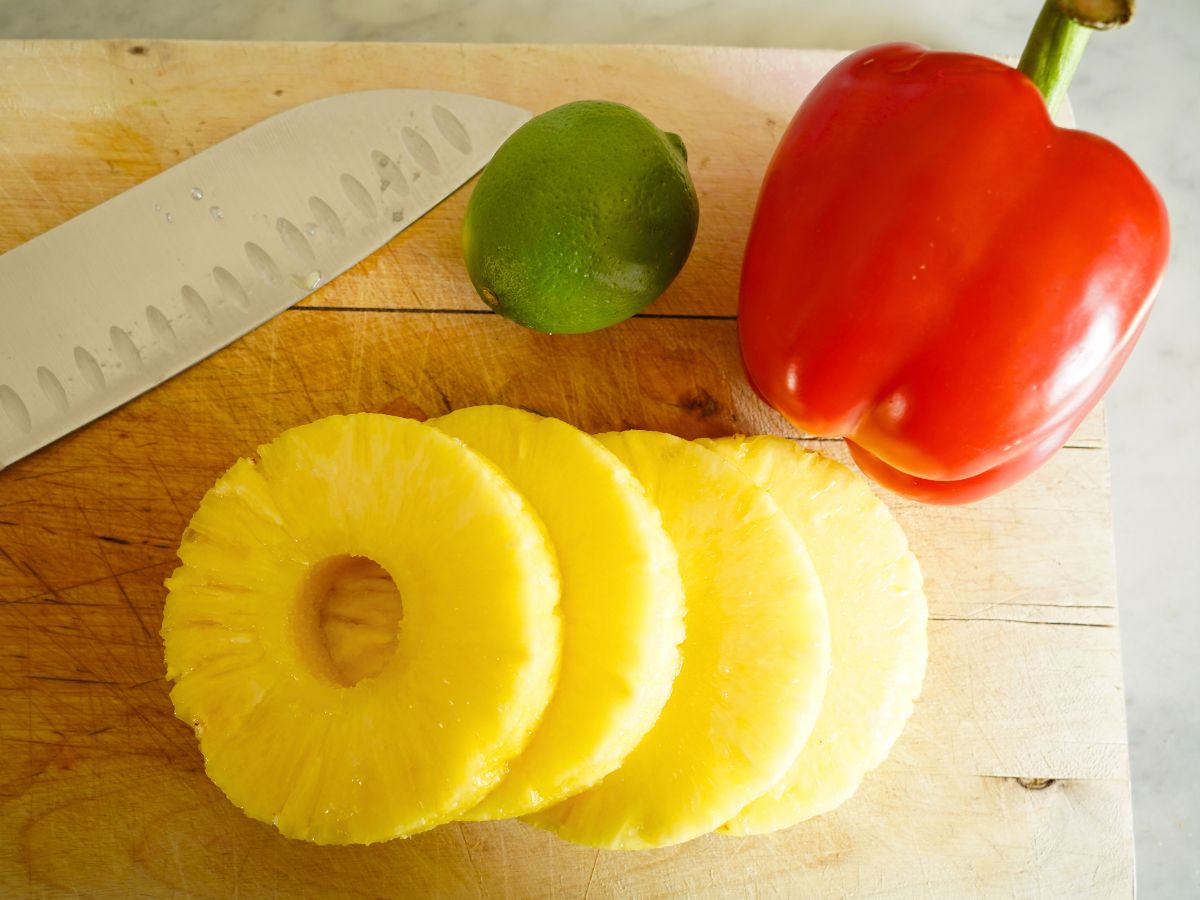 red pepper, lime, sliced pineapple with knife on cutting board