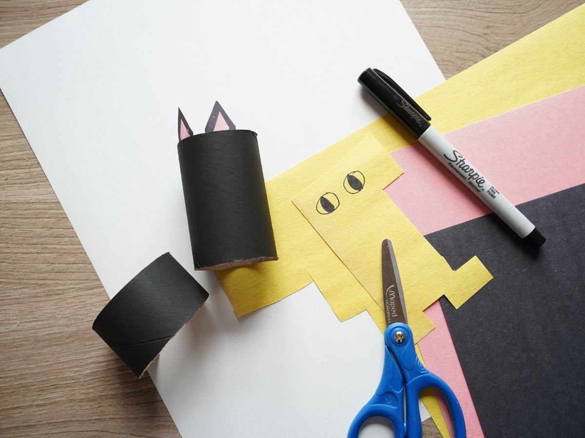 black toilet roll with cat ears glues inside and construction paper eyes on paper