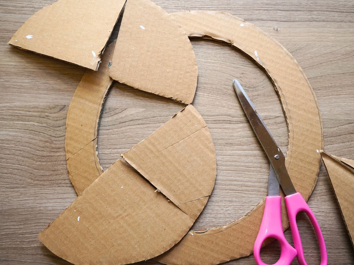 cardboard cut into a circle wreath form with pair of scissors on table