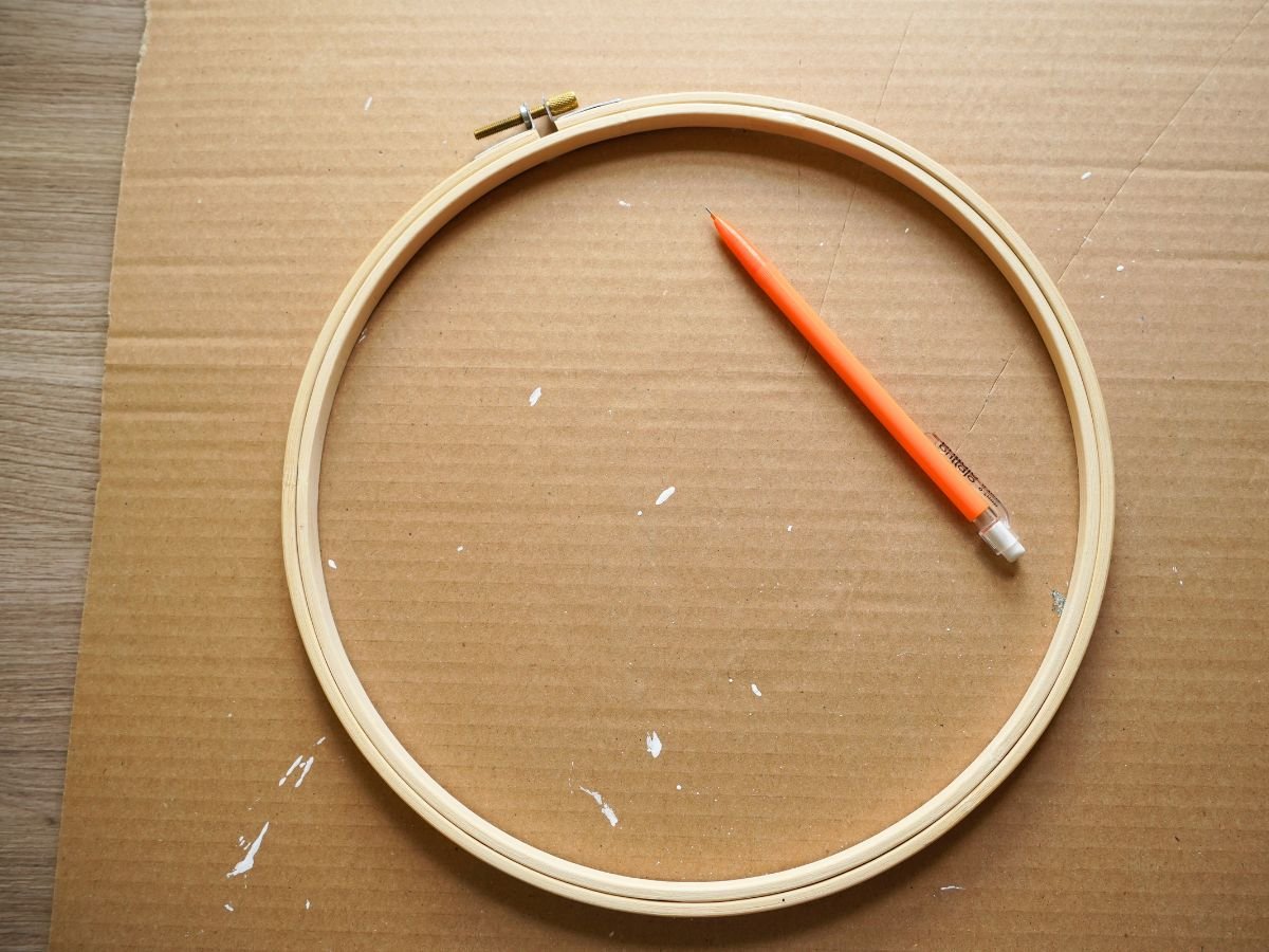 embroidery hoop being traced on sheet of cardboard with pencil