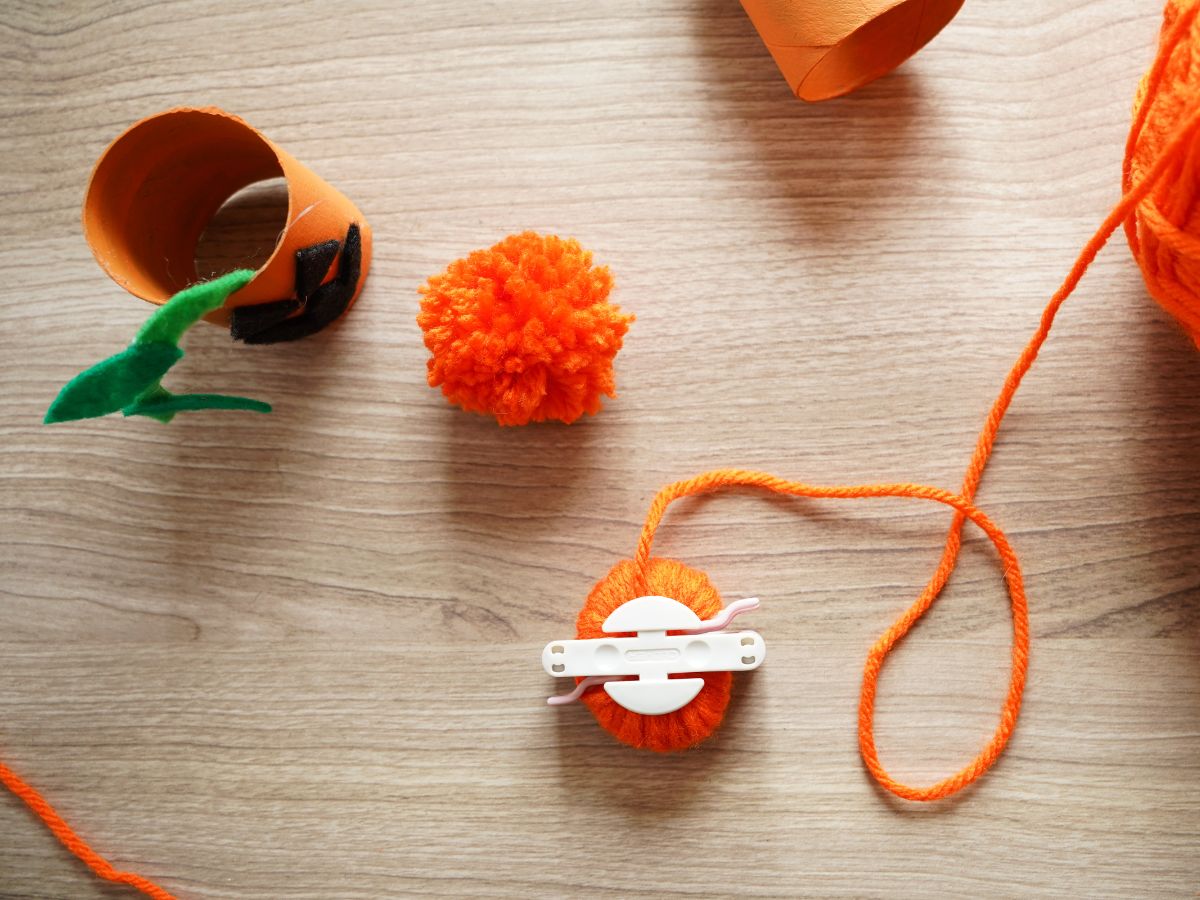 orange yarn pom pom and pom pom maker tool