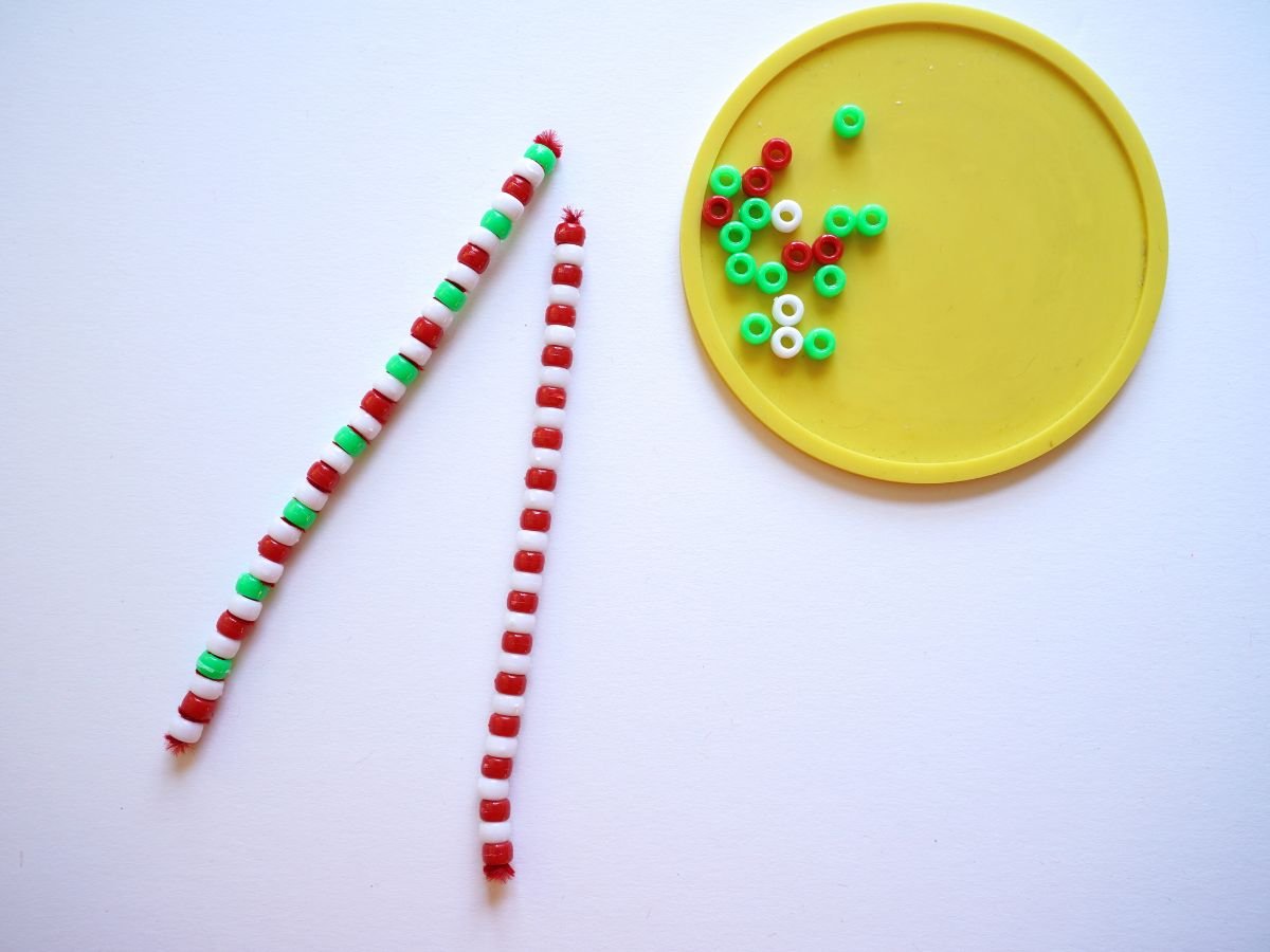 two pipe cleaners with candy cane colored beads on them