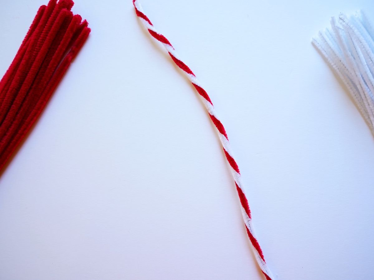 white and red pipe cleaners twisted together to make a candy cane stick