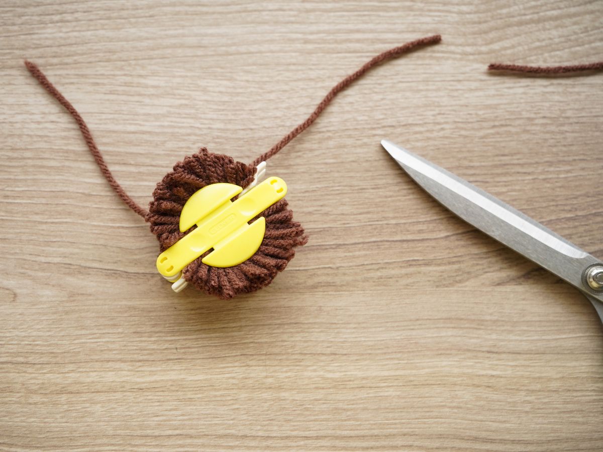 brown yarn trimmed in pom pom maker tool