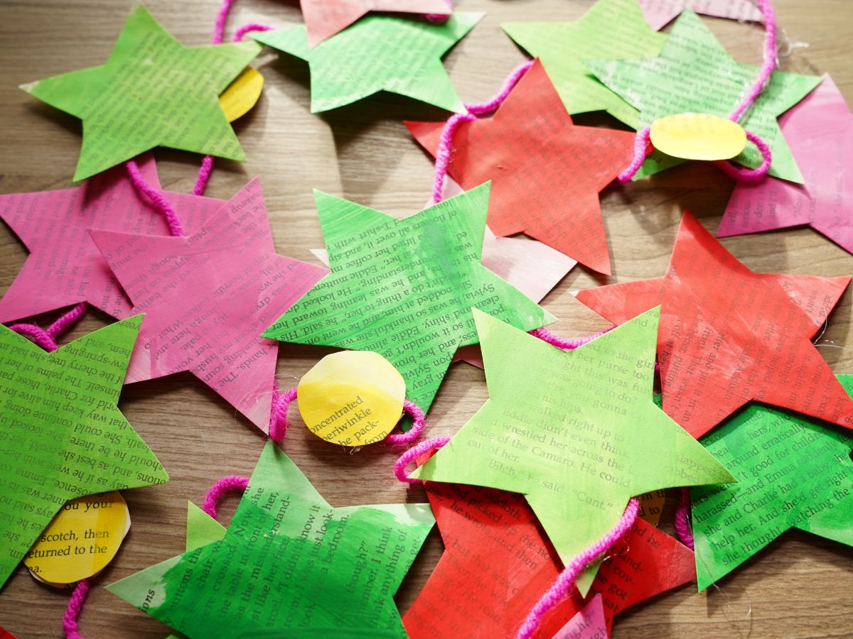 diy paper star garland in a pile on a table with pink, green, red stars cut from book pages