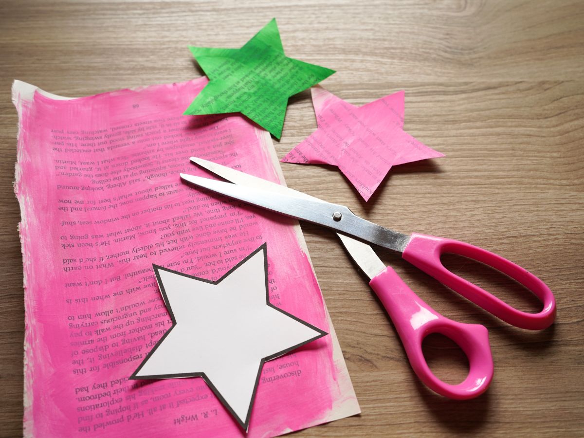 image of book page painted pink with star template on page and pair of scissors and green and pink stars cut from the page