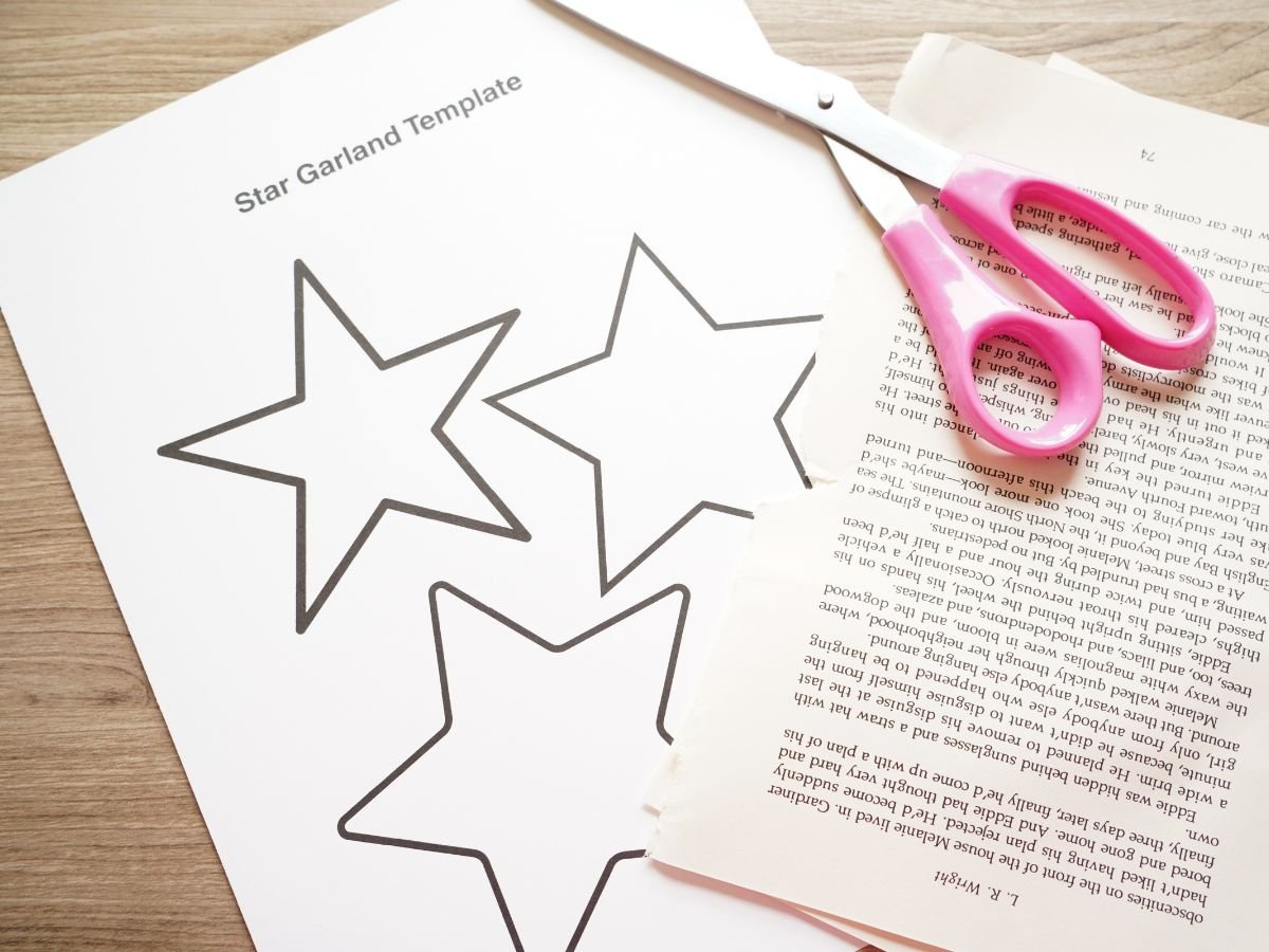 image of printable star garland template, pair of scissors and pages ripped from a book