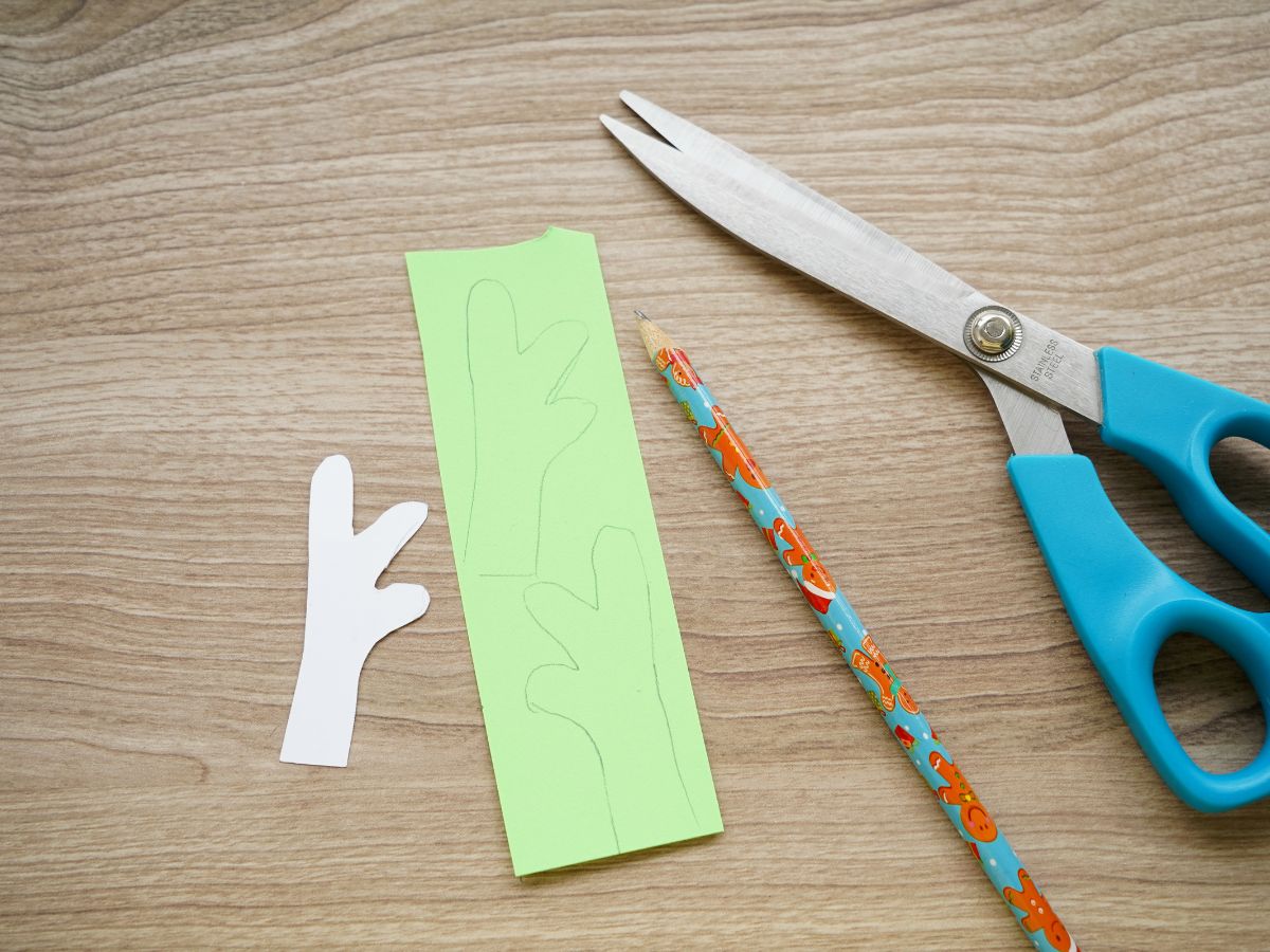 printable antler template cut out and traced on green card stock beside a pencil and scissors