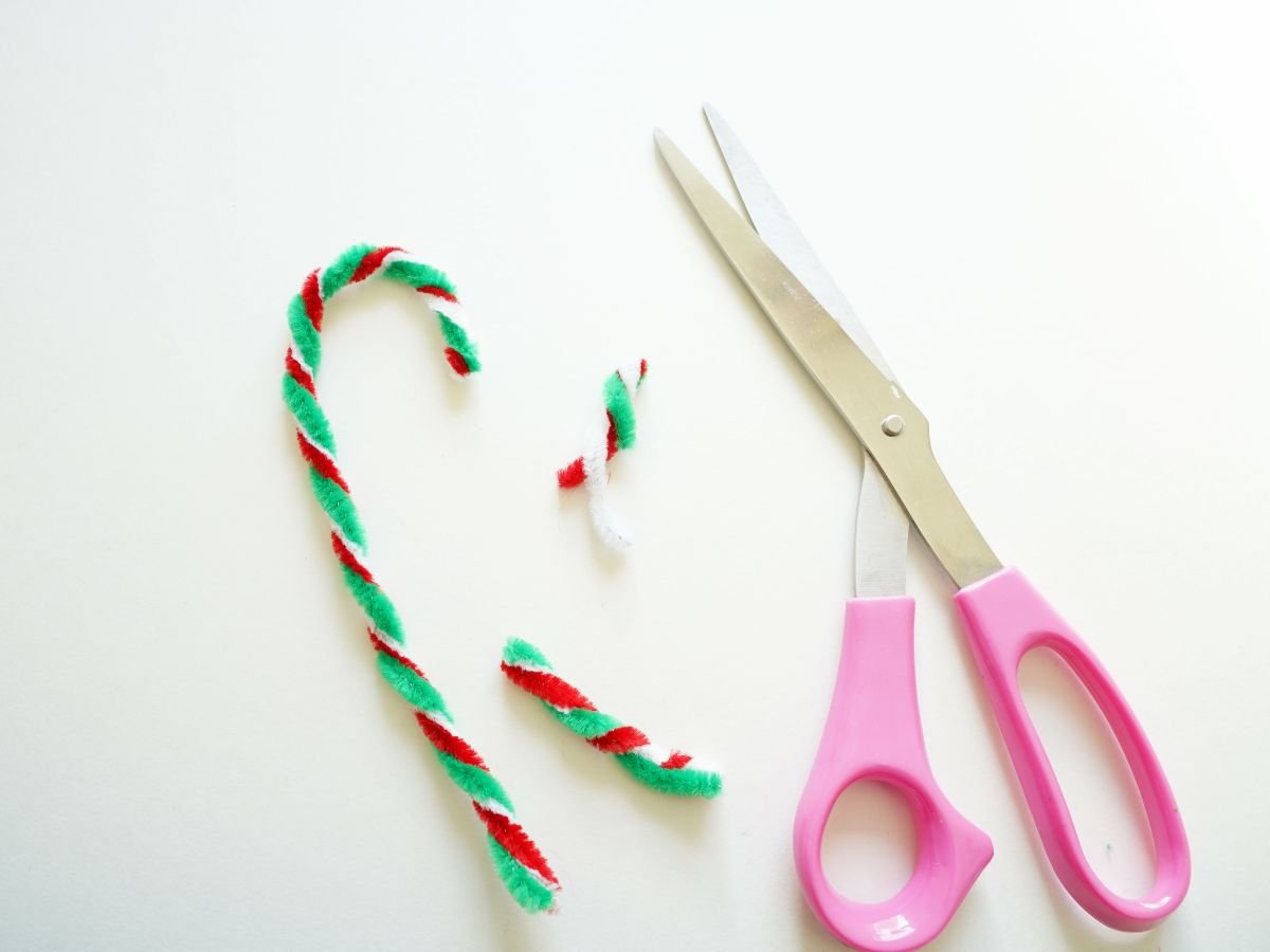 red, white, and green pipe cleaners shaped into candy cane with pair of scissors