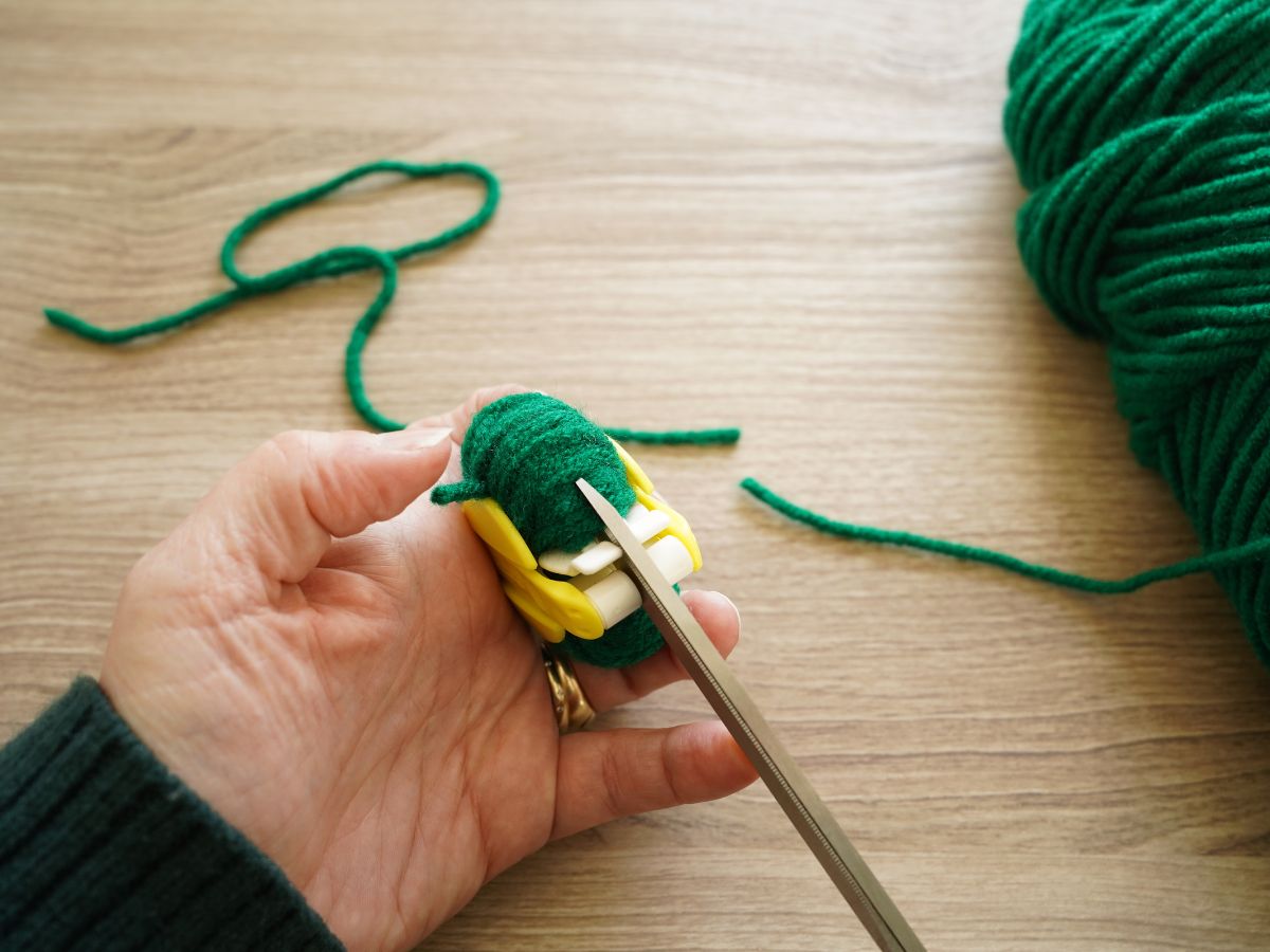 scissors cutting down the middle of a pom pom maker tool