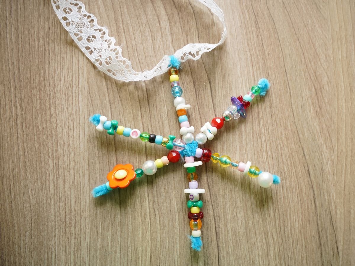 beaded snowflake with loop of ribbon being attached to one arm of snowflake