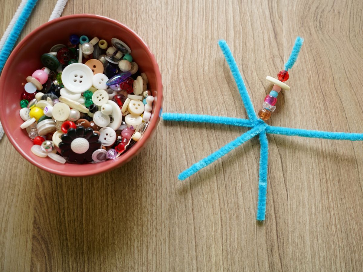bowl of beads and buttons beside pipe cleaner snowflake with beads on snowflake arm