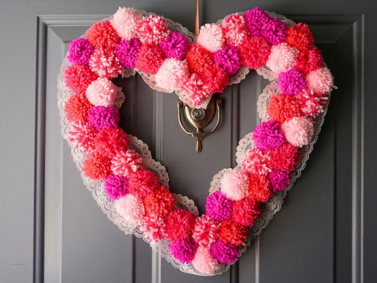 finished pom pom heart wreath with lace trim hanging on door