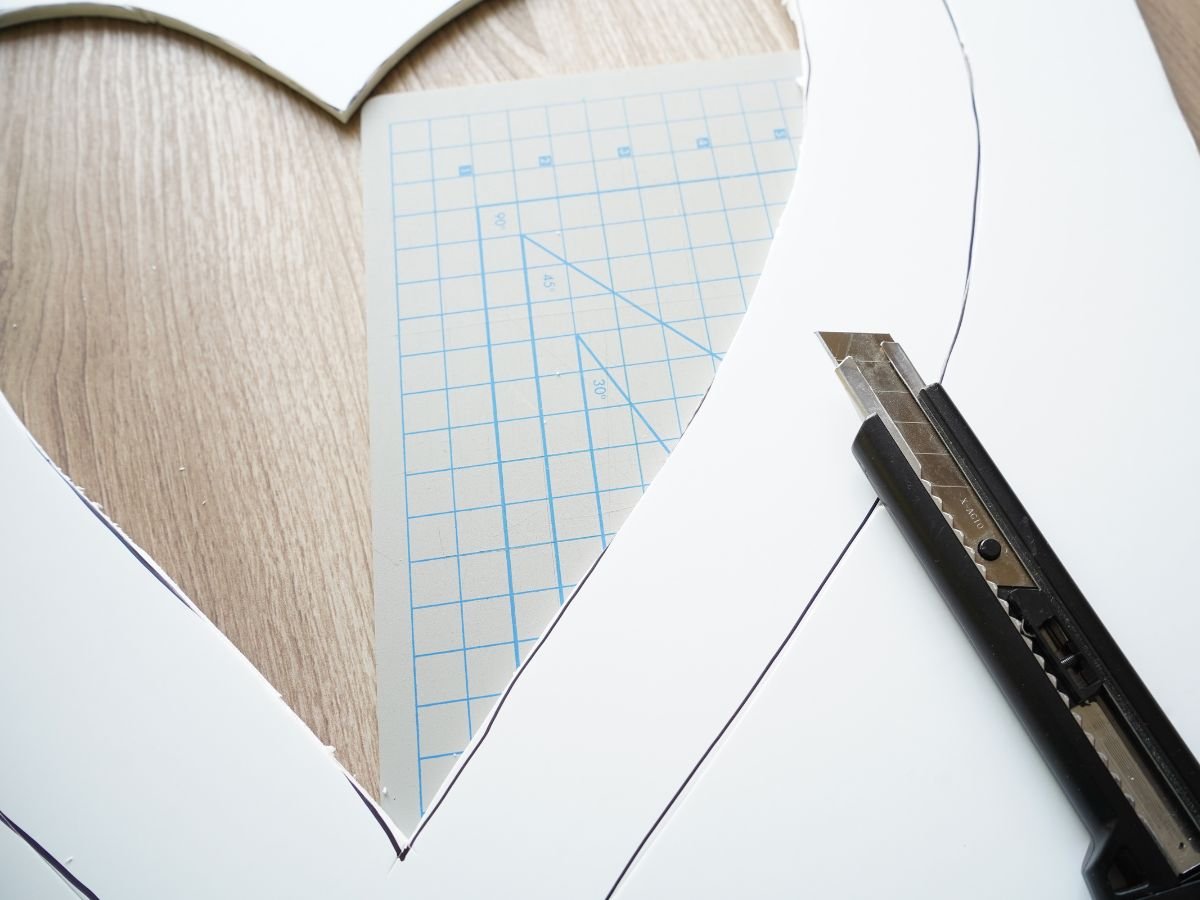 heart shaped being cut out of foam core sheet with utility knife