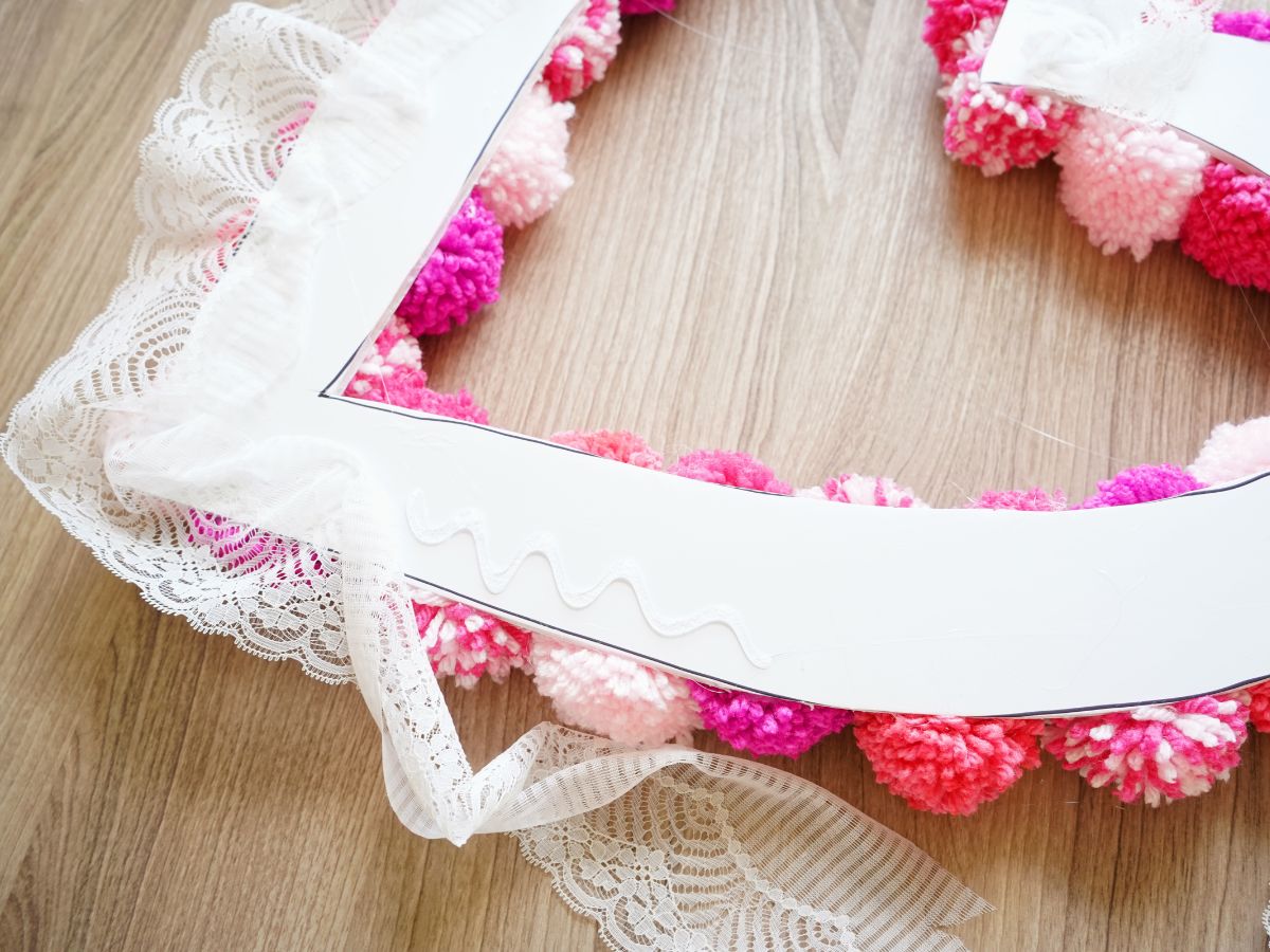 piece of lace trim being glued onto foam core heart wreath form