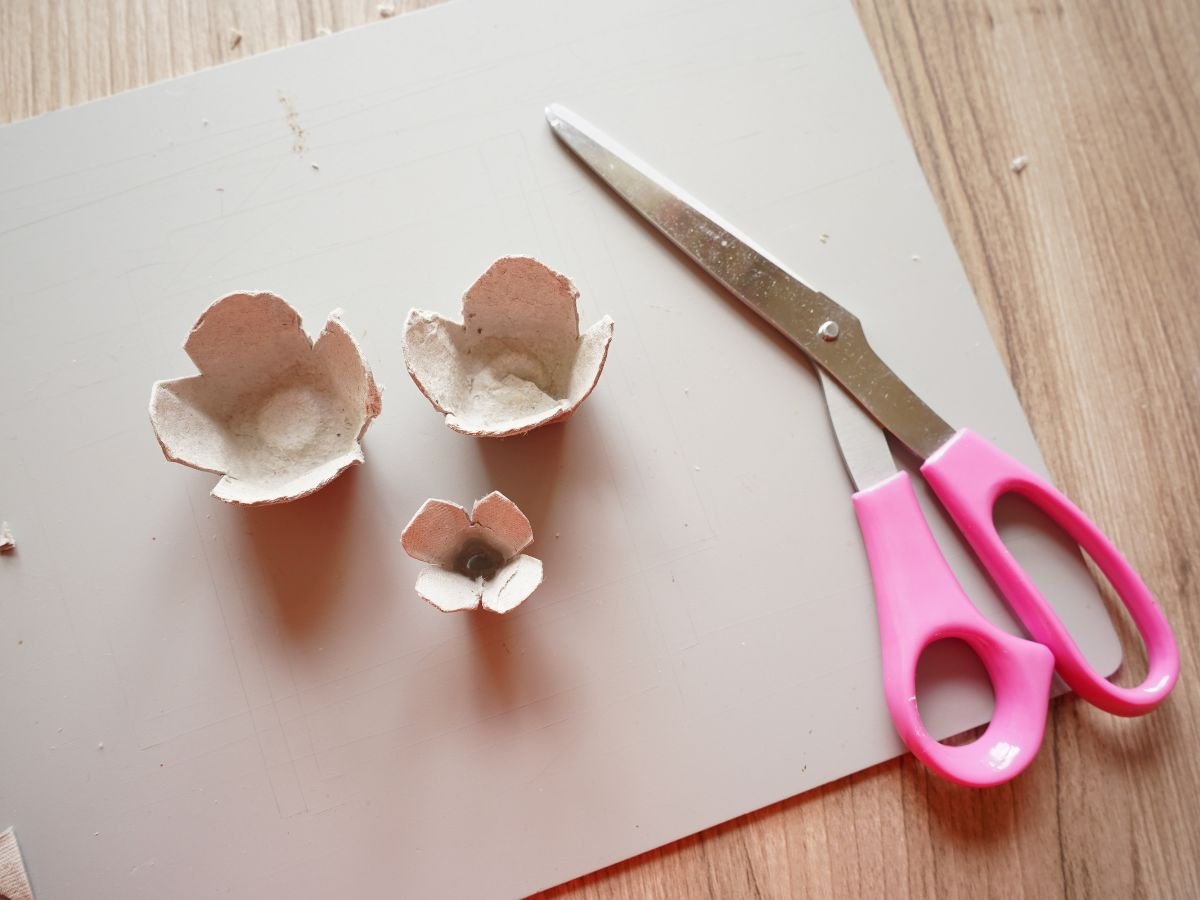 egg carton cells cut into layers of a rose with pair of scissors