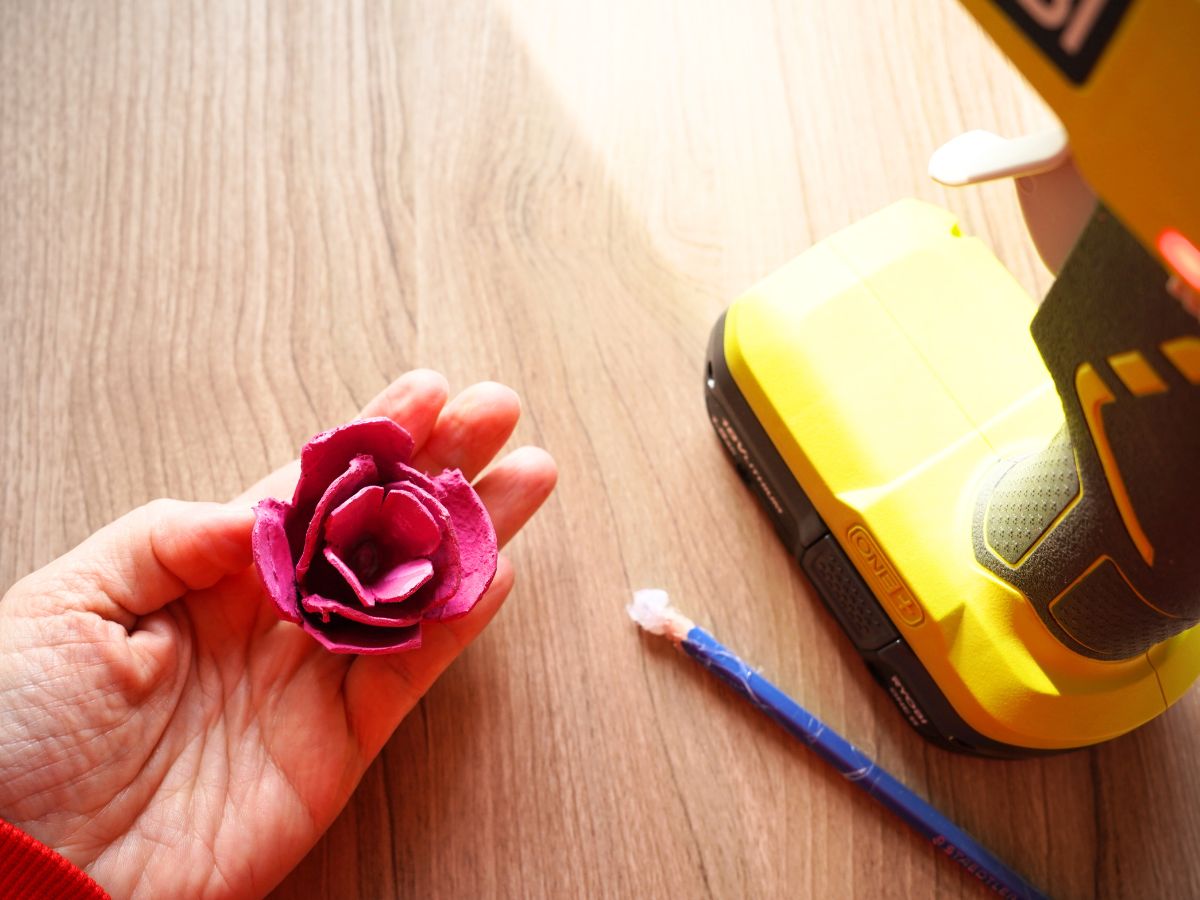 final egg carton rose in woman's hand beside glue gun