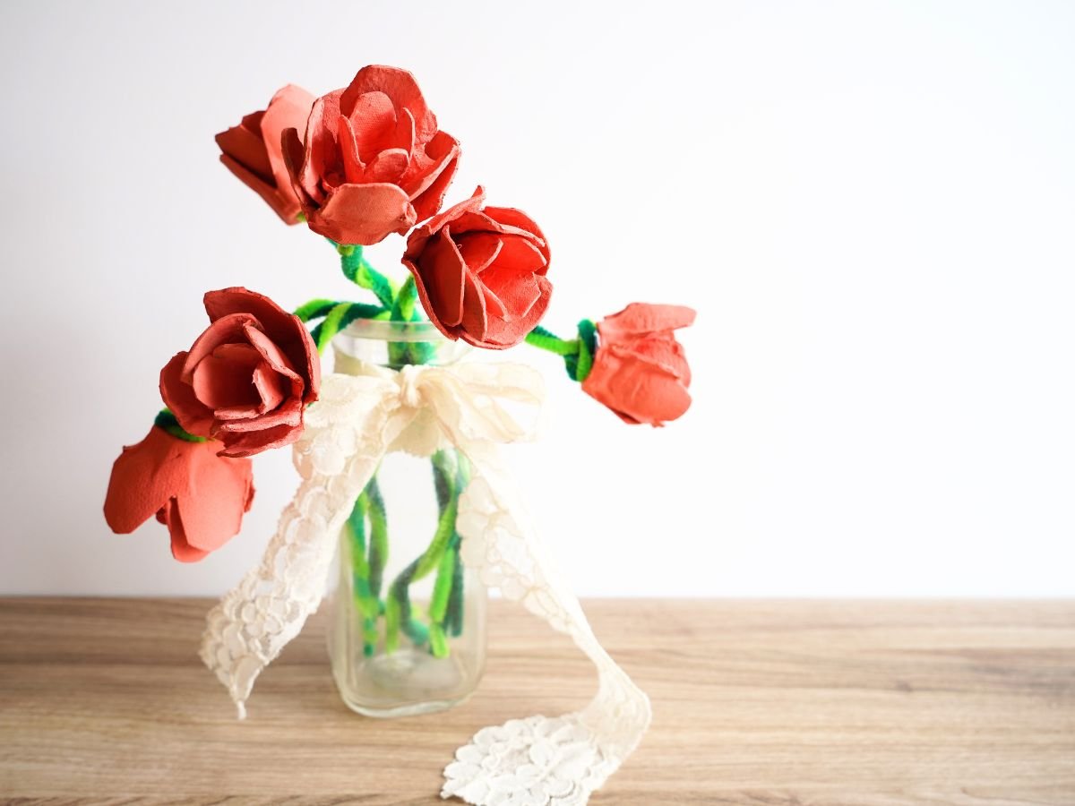 glass vase filled with egg carton roses and wrapped in lace ribbon