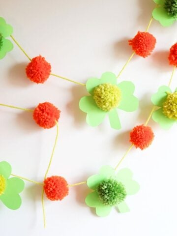 close up of pom pom clover st patrick's day garland hanging on wall