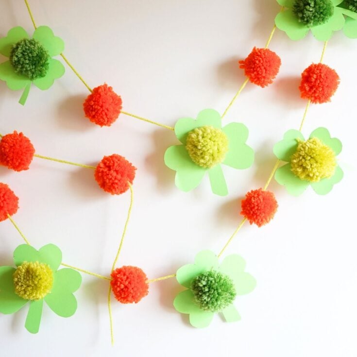 close up of pom pom clover st patrick's day garland hanging on wall