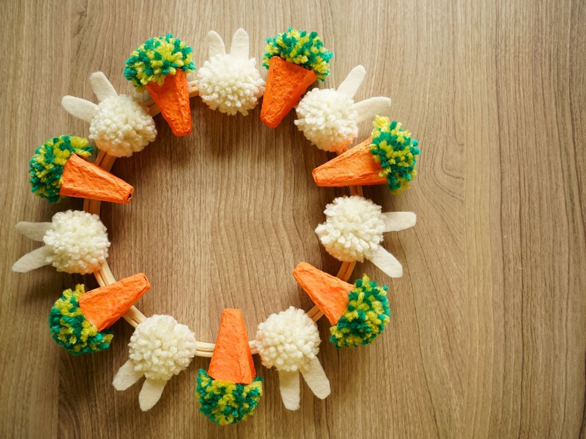 finished easter wreath that is covered with egg carton carrots and pom pom Easter bunnies