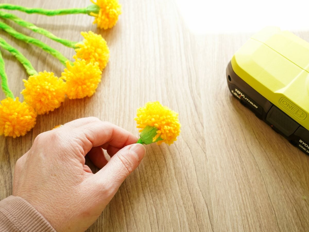 dandelion pom pom pressed into egg carton flower base being held in hand