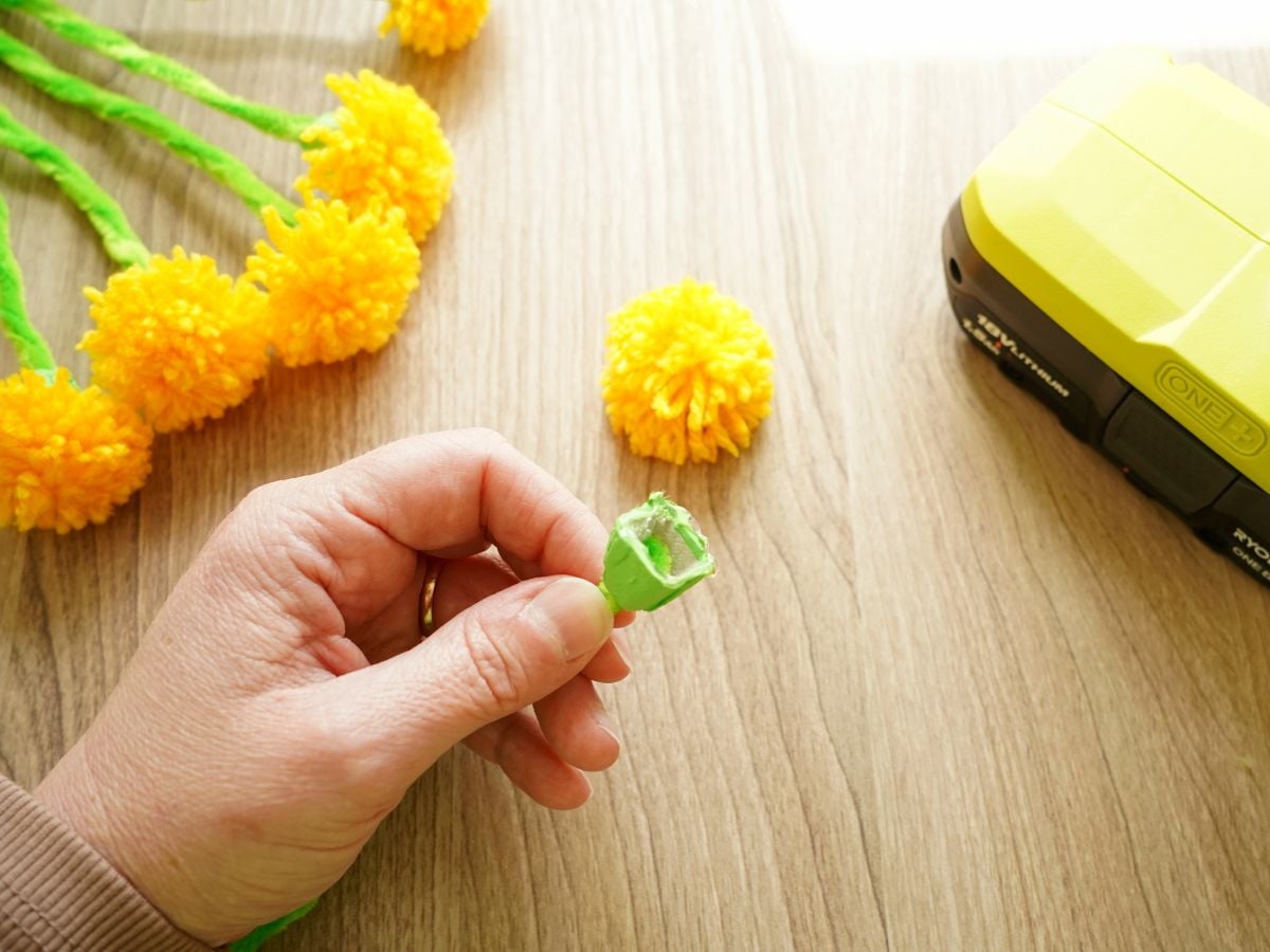 hand holding egg carton flower bulb with hot glue inside of it
