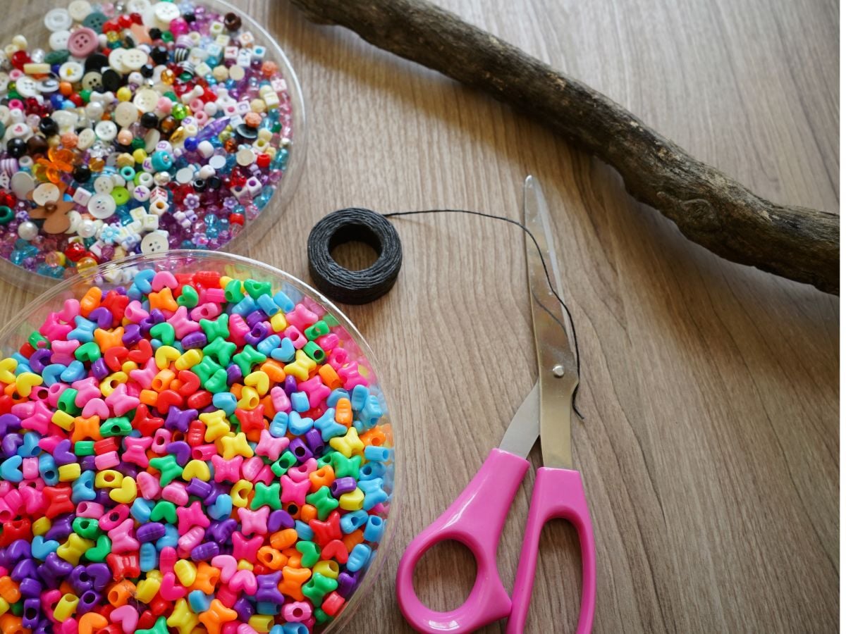 bowls of beads, stick, scissors and waxed linen for wind chime