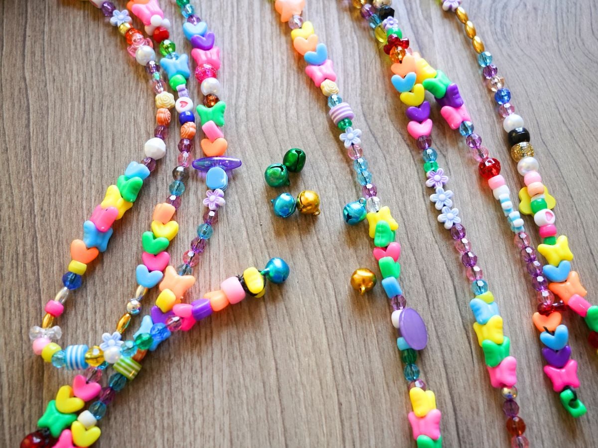 close up of jingle bells tied on ends of beaded wind chime strands