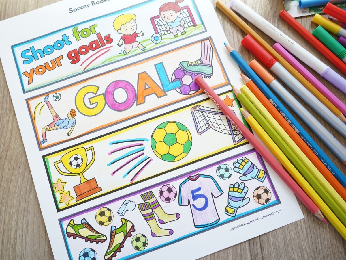 pile of markers and pencil crayons with fully colored soccer-themed bookmarks on table