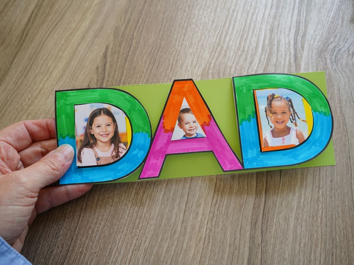 woman's hand holding printable father's day picture frame craft that kids colored