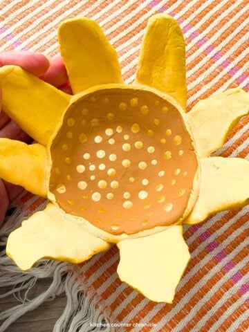 close up of hand holding a clay sunflower craft bowl