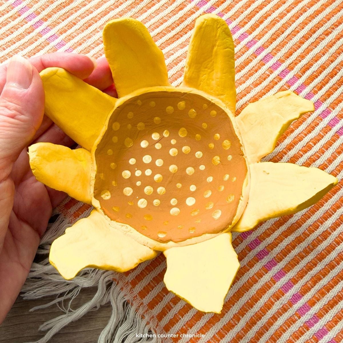 close up of hand holding a clay sunflower craft bowl
