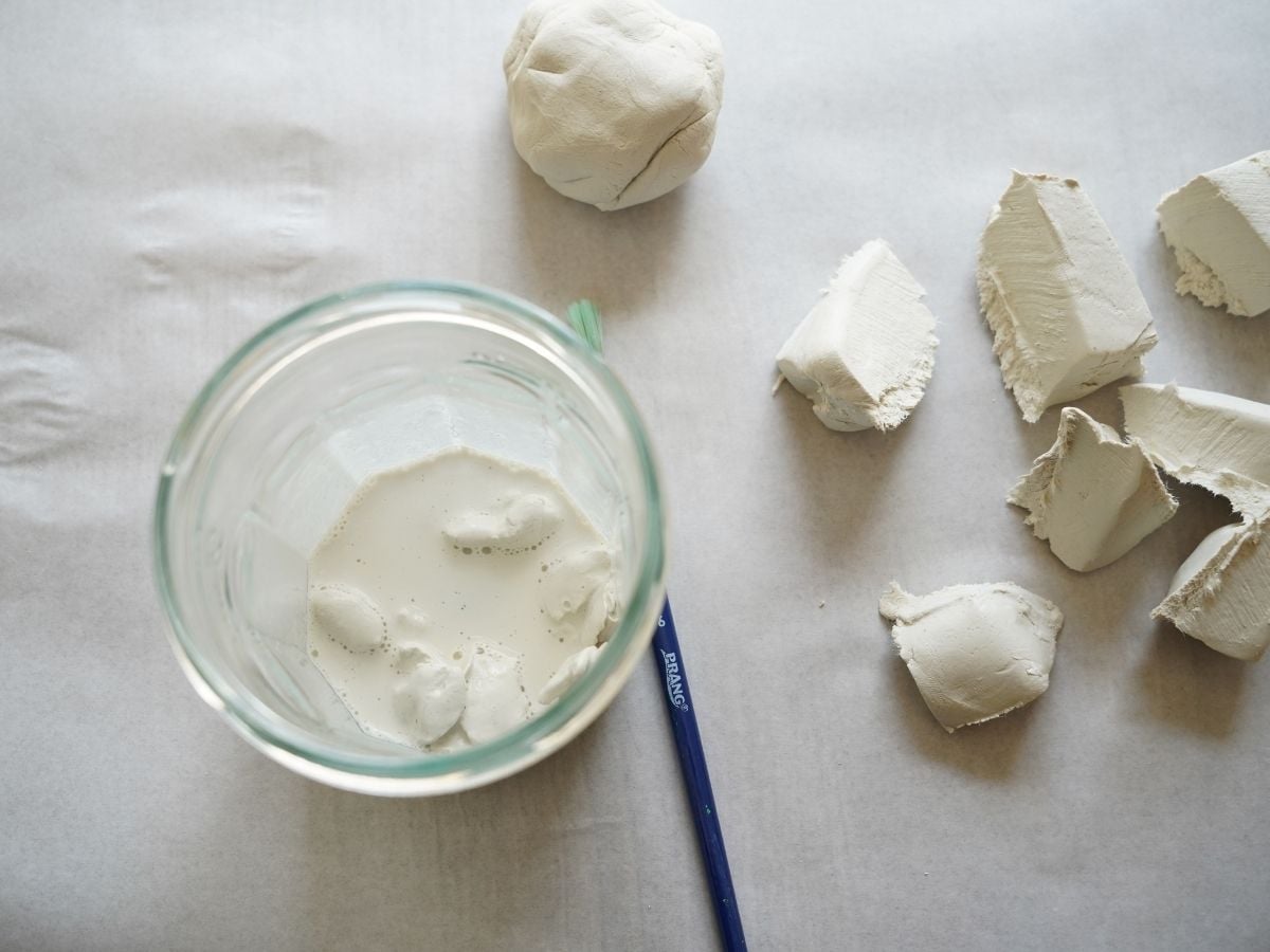 small jar filled with clay slip and chunks of clay