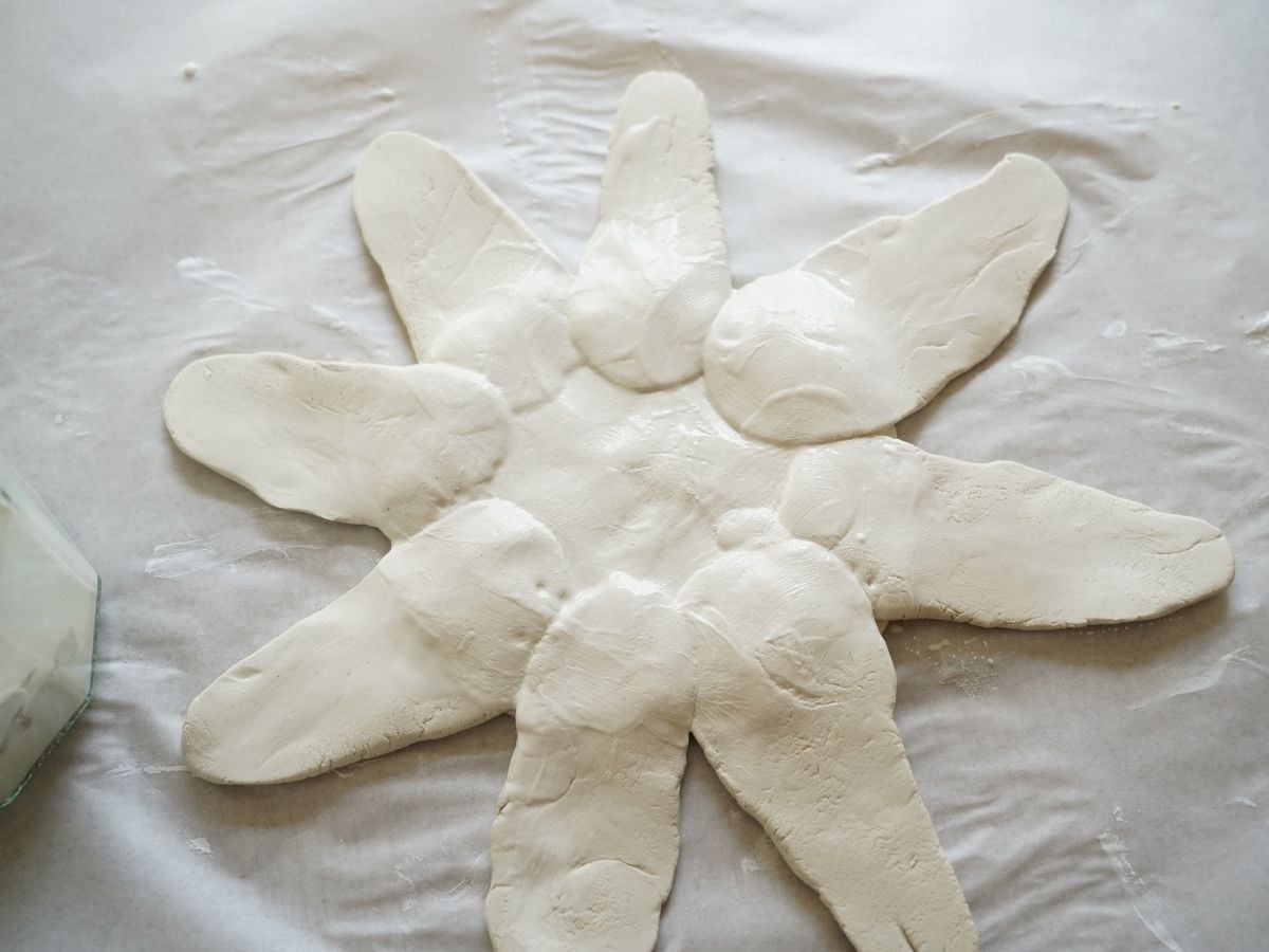 underside of sunflower pinch pot wet with clay slip