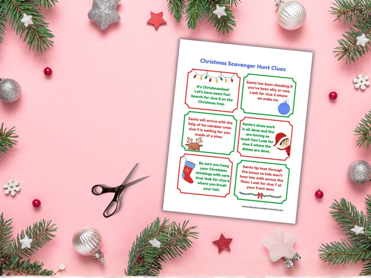 one sheet of christmas gift scavenger hunt clues with a pair of scissors and surrounded by Christmas greenery